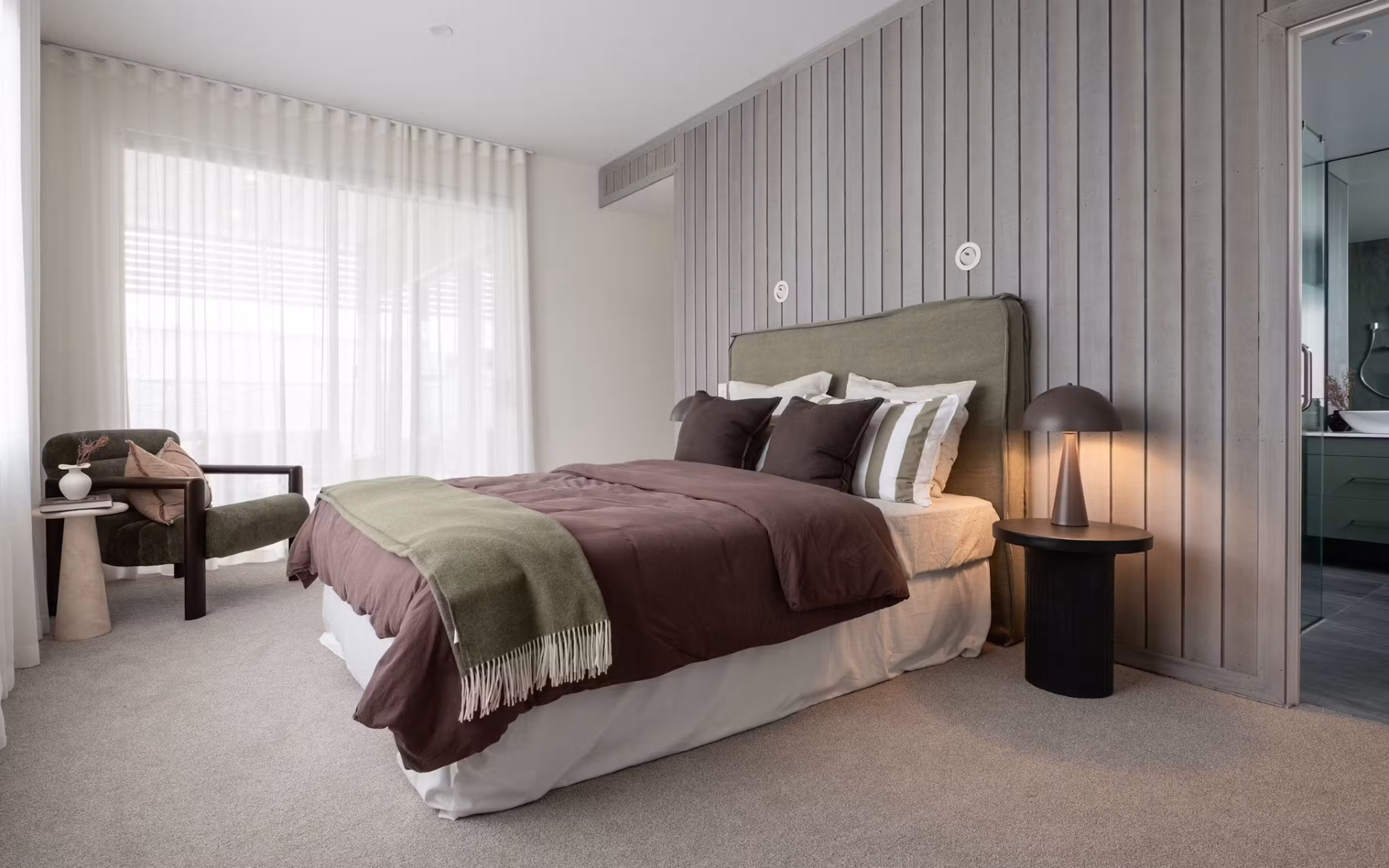 A sophisticated contemporary bedroom featuring warm textures, natural tones and elegant timber detailing.