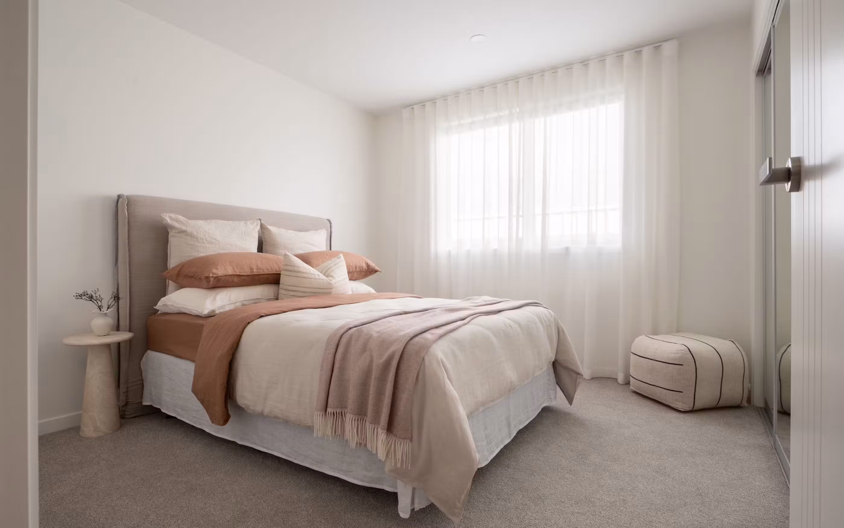 A bright and welcoming bedroom combining natural light, soft textures and a calming neutral palette.